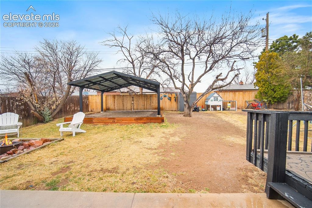 Image 16 of 18: Spacious backyard featuring a metal-framed covered structure, wooden privac