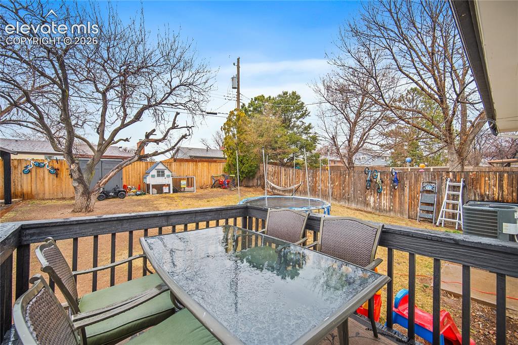 Image 17 of 18: Expansive backyard featuring a wood fence, mature trees, and a wooden deck