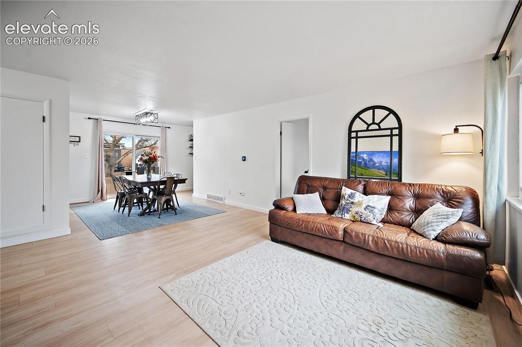 Image 2 of 18: Light wood-finish flooring extends through the open living and dining areas