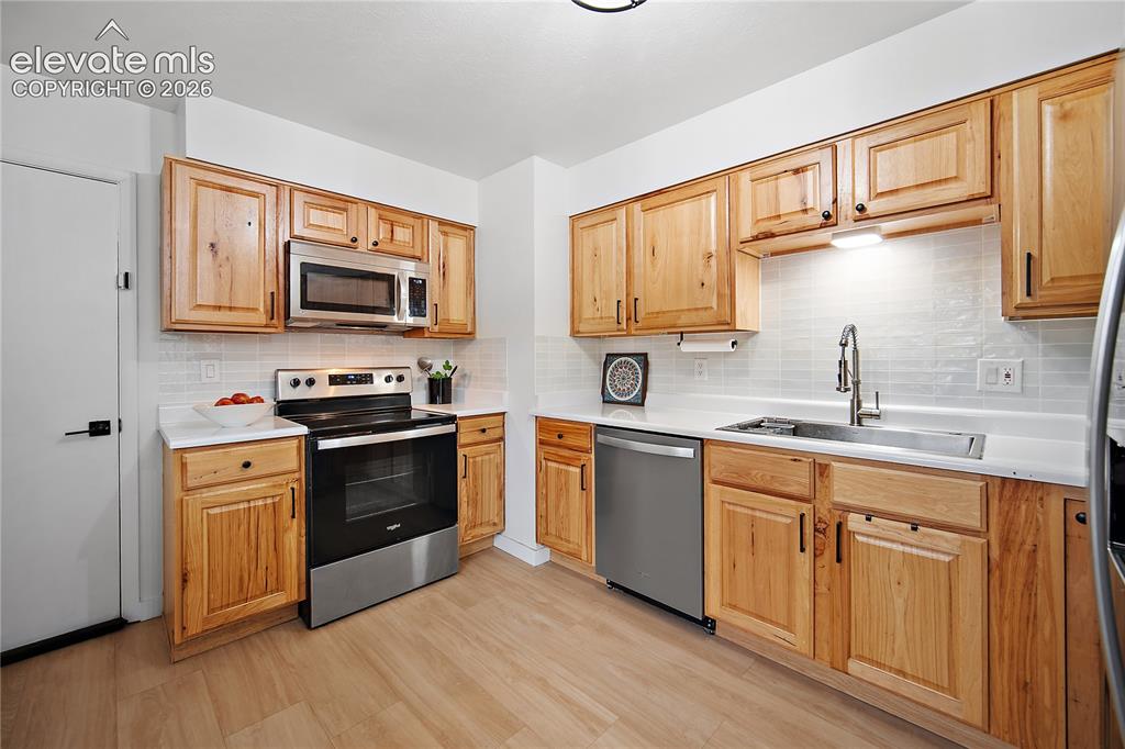 Image 5 of 18: Kitchen featuring wood-finish cabinetry, stainless steel appliances, white 