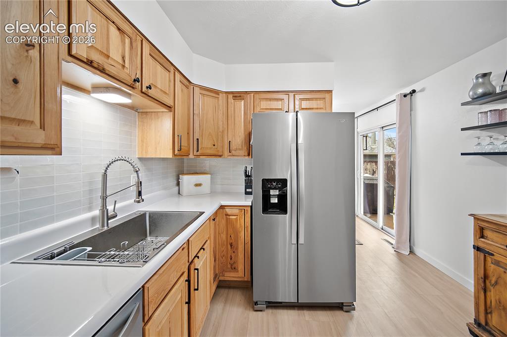 Image 6 of 18: Kitchen featuring wood cabinetry, light countertops, a stainless steel side