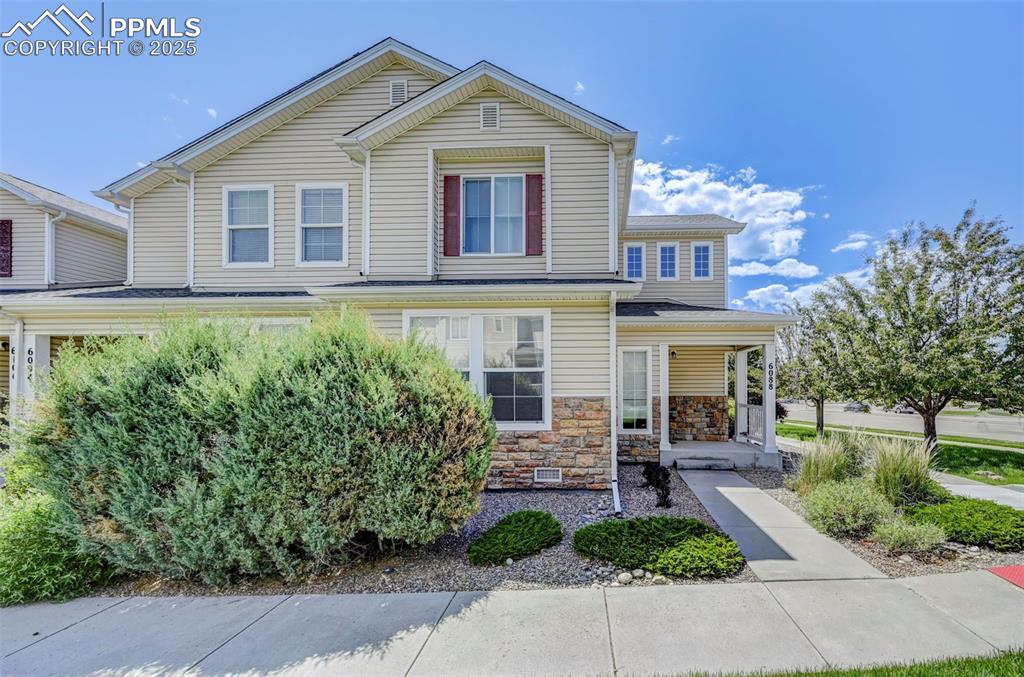 Image 13 of 31: Traditional-style home with covered porch and stone siding