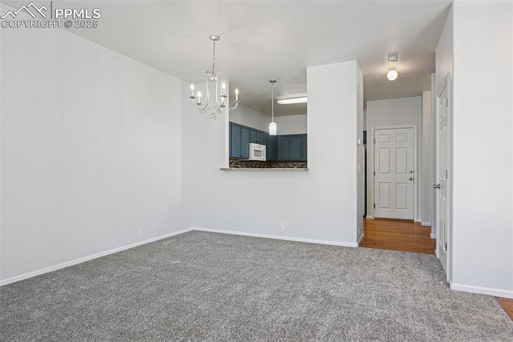 Image 15 of 31: Carpeted spare room featuring a chandelier and baseboards