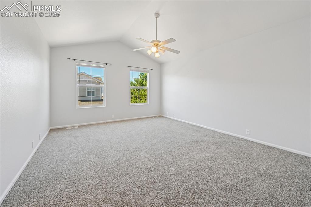 Image 23 of 31: Carpeted spare room with vaulted ceiling and ceiling fan