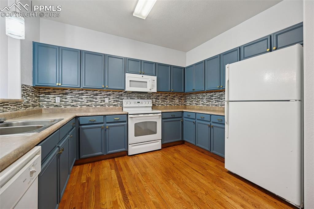 Image 7 of 31: Kitchen with white appliances, blue cabinetry, light wood-style flooring, a