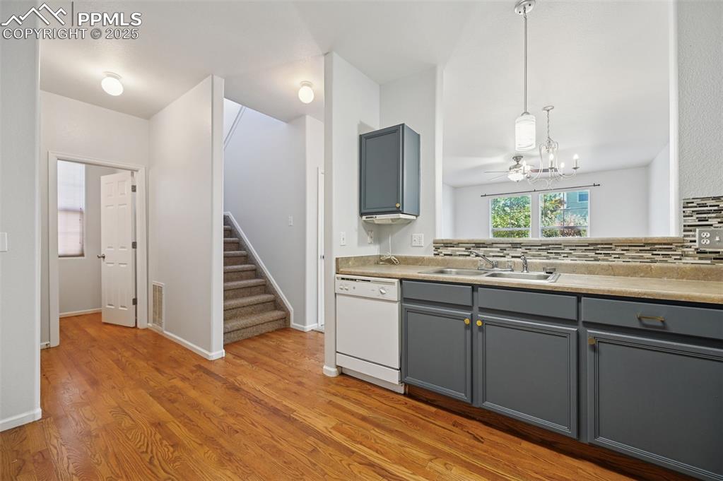Image 8 of 31: Kitchen with gray cabinets, dishwasher, light wood-type flooring, a chandel