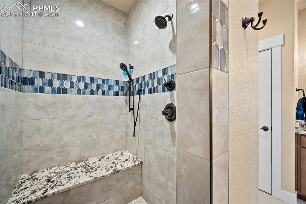 Image 17 of 49: Tile shower with dual shower heads and quartz bench.