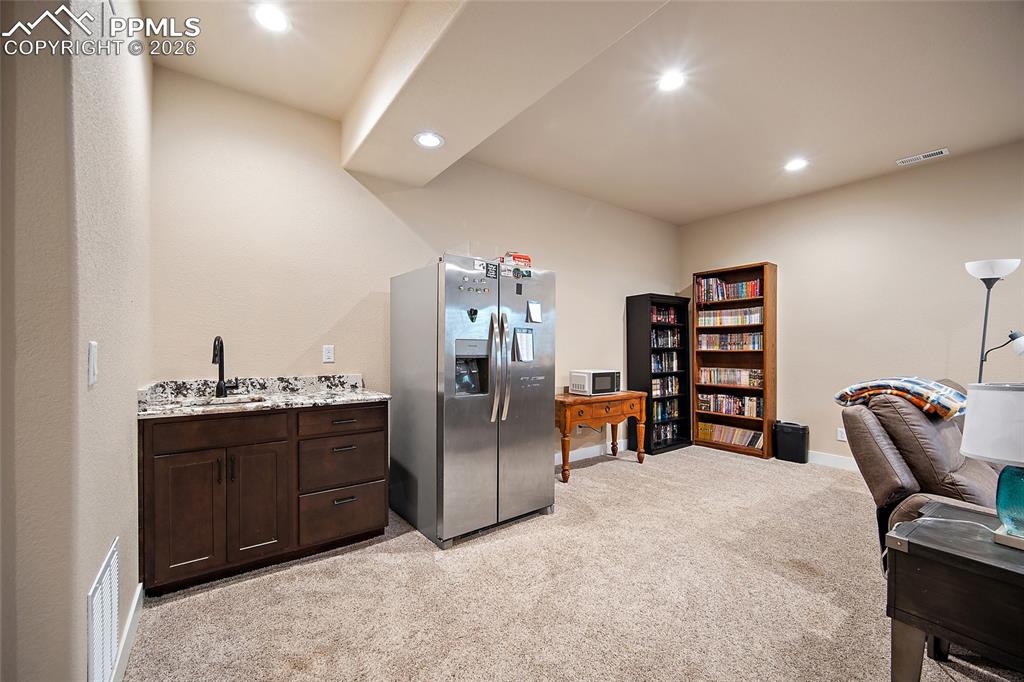 Image 29 of 49: Lower level family room with wet bar, quartz countertops and full size refr