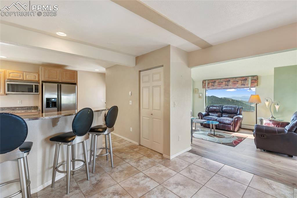 Image 14 of 48: Kitchen with a kitchen bar, dark stone counters, stainless steel appliances