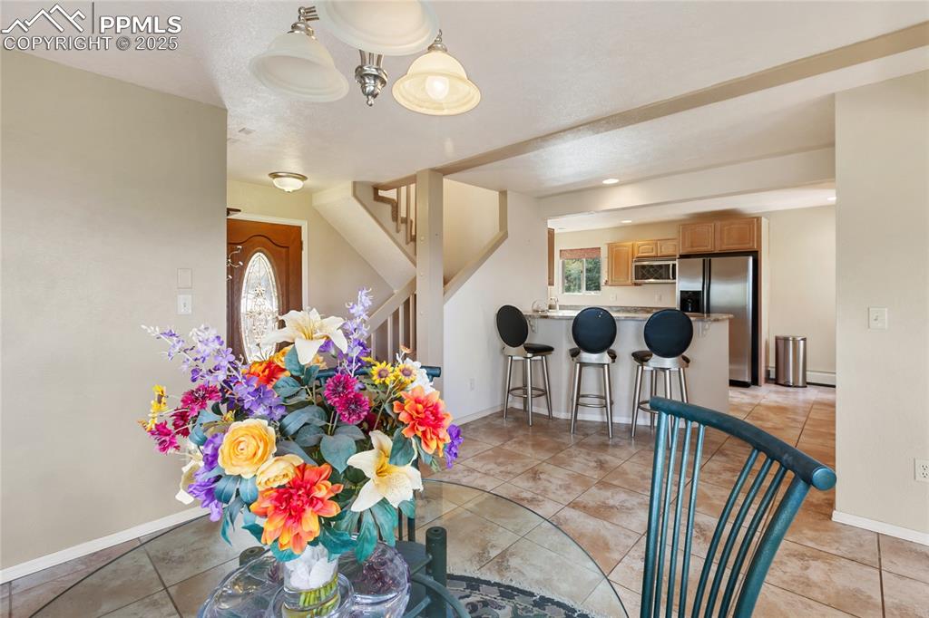 Image 16 of 48: Dining space with light tile patterned floors and stairway
