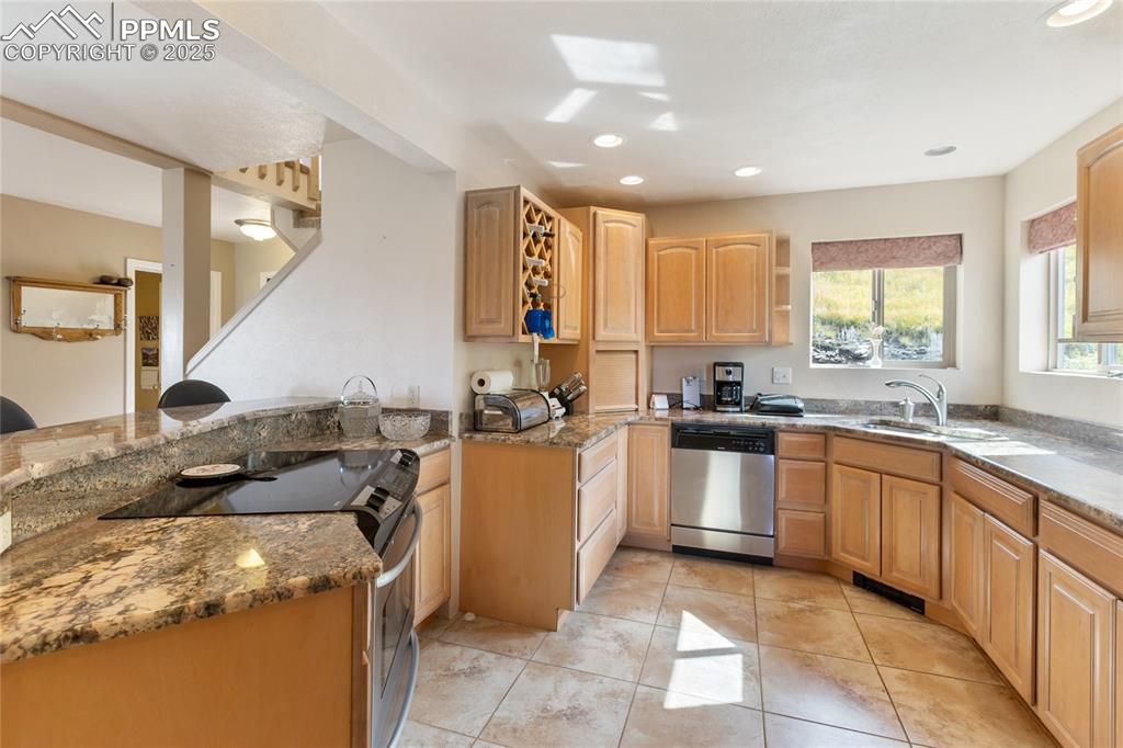 Image 17 of 48: Kitchen featuring appliances with stainless steel finishes, light stone cou