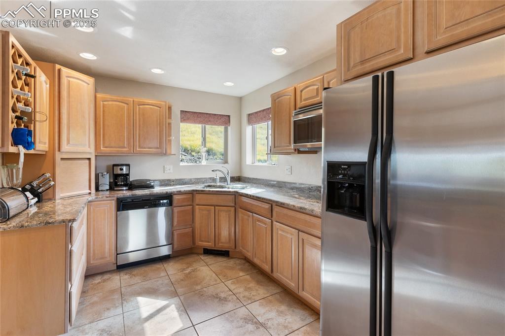 Image 18 of 48: Kitchen with appliances with stainless steel finishes, light stone counters