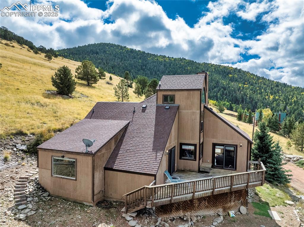 Image 2 of 48: Rear view of property with a forest view, roof with shingles, a deck with m
