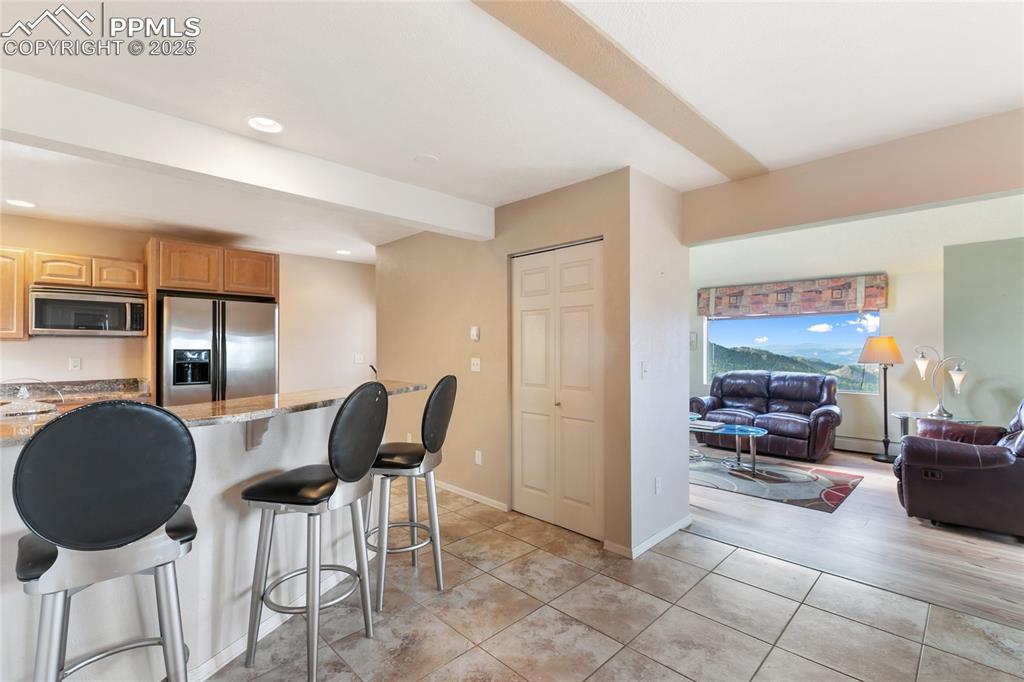 Image 22 of 48: Kitchen featuring a kitchen breakfast bar, dark stone countertops, applianc