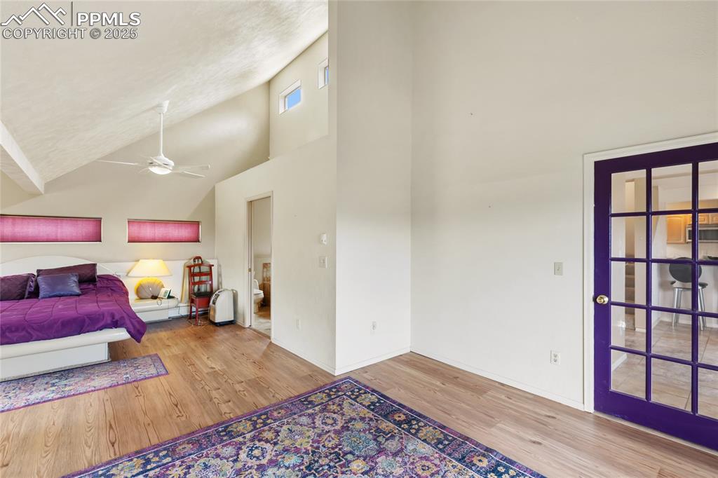Image 27 of 48: Bedroom with high vaulted ceiling, light wood-style floors, ensuite bathroo