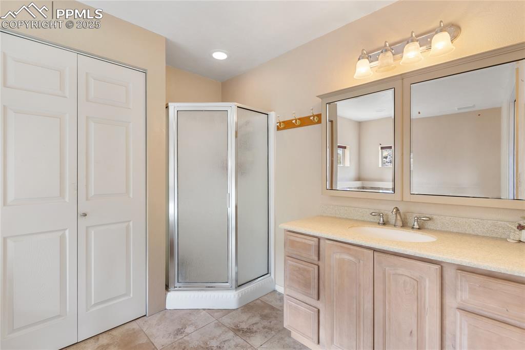 Image 28 of 48: Full bath with a shower stall, vanity, a closet, and light tile patterned f