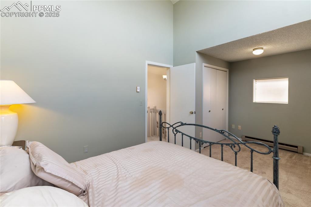 Image 31 of 48: Carpeted bedroom with baseboard heating, a textured ceiling, a closet, and 
