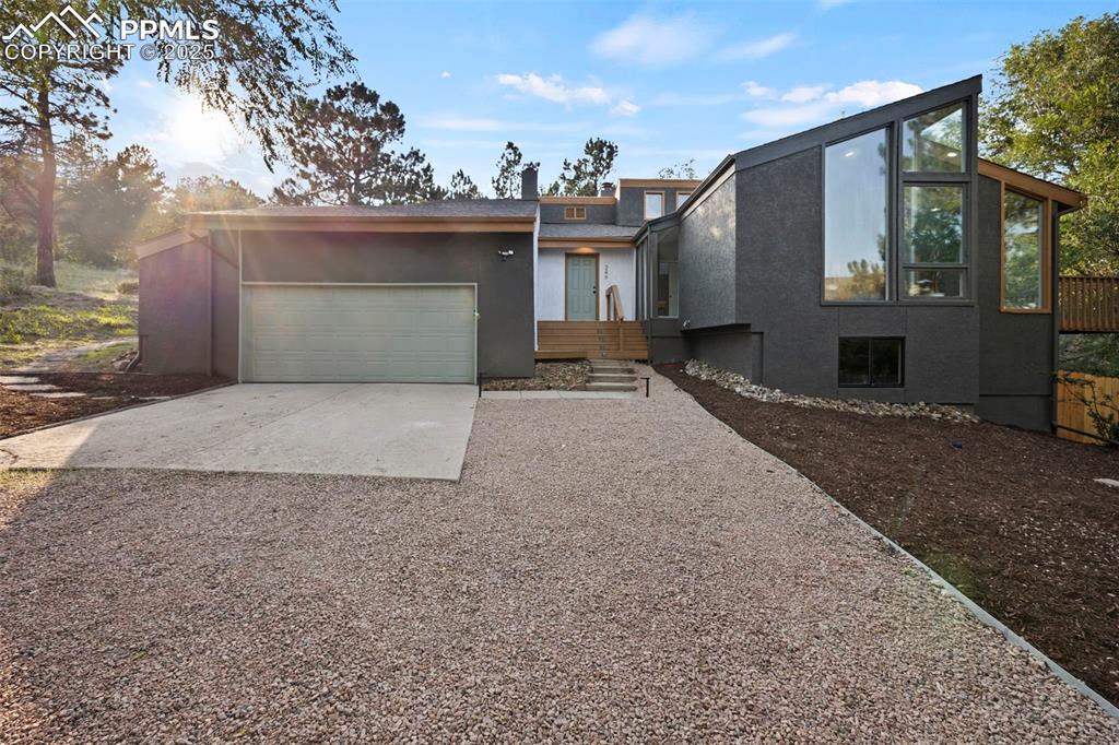 Caption: Mid-century home with driveway, stucco siding, and an attached garage
