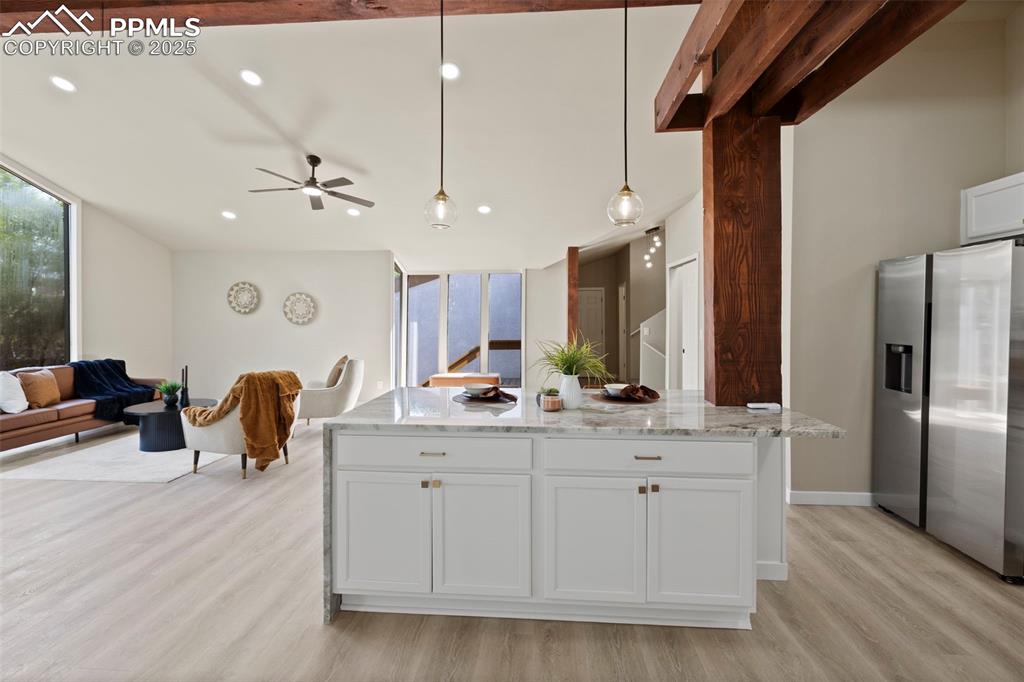 Image 12 of 50: Kitchen featuring white cabinetry, recessed lighting, stainless steel fridg