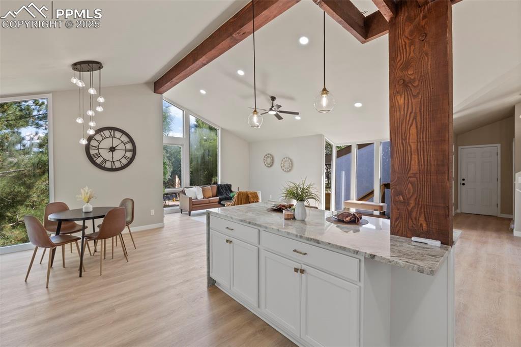 Image 13 of 50: Kitchen with hanging light fixtures, light stone countertops, beam ceiling,