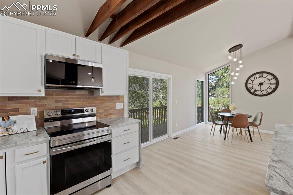 Image 14 of 50: Kitchen featuring appliances with stainless steel finishes, backsplash, lig