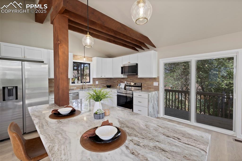 Image 16 of 50: Kitchen featuring light stone countertops, pendant lighting, appliances wit