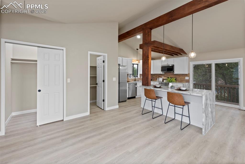 Image 3 of 50: Kitchen featuring a breakfast bar, decorative light fixtures, white cabinet