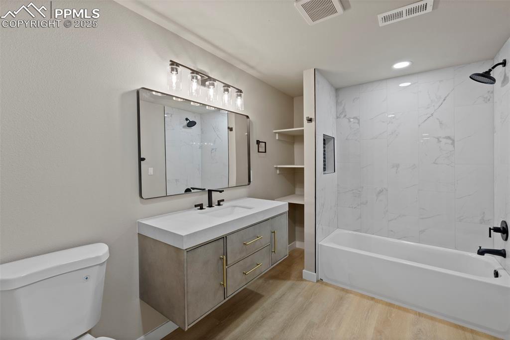 Image 44 of 50: Bathroom with light wood finished floors, a combined bath / shower with mar