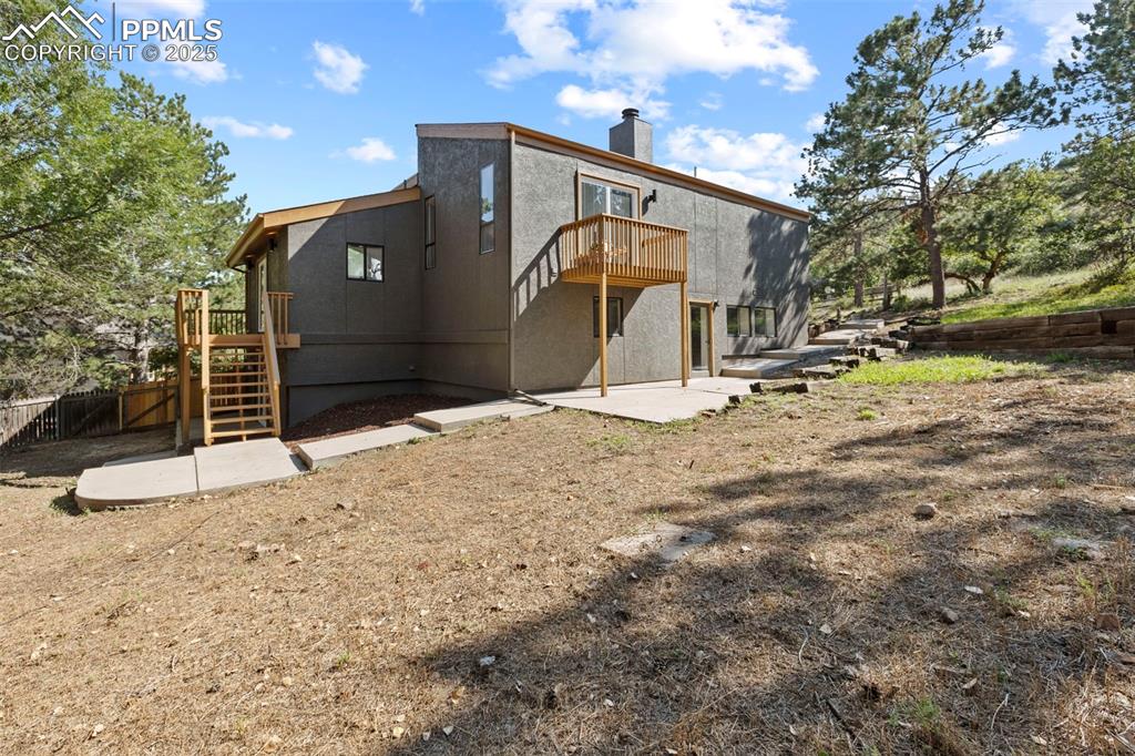 Image 50 of 50: Rear view of house with stairway, a patio area, a chimney, and stucco sidin