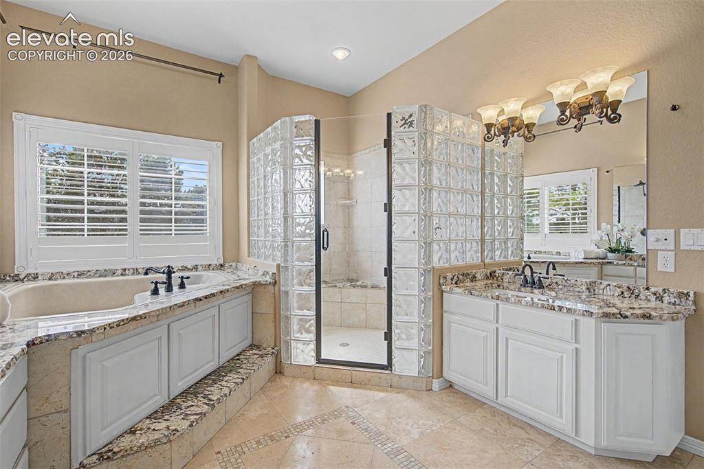 Image 24 of 42: Relax in the corner jetted tub framed by elegant plantation shutters, or st