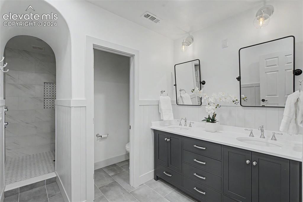 Image 36 of 42: This pristine lower-level luxury bathroom features a beautiful dual-sink va