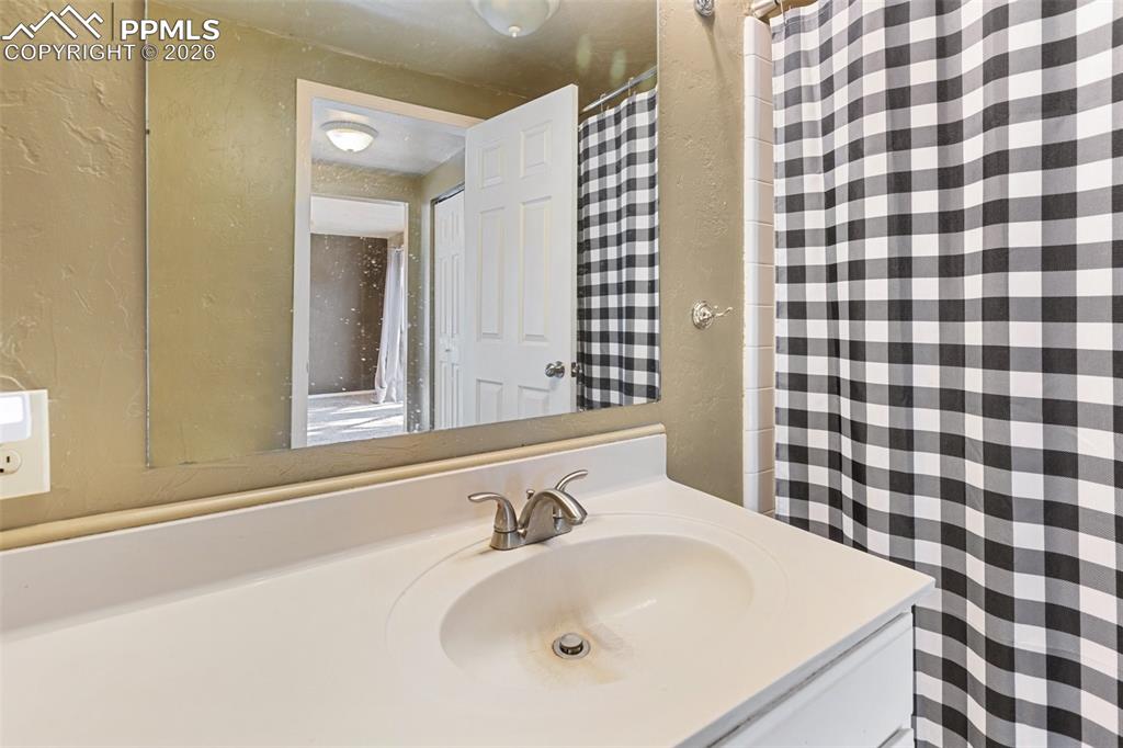 Image 19 of 36: Full bath featuring vanity, a textured wall, and curtained shower