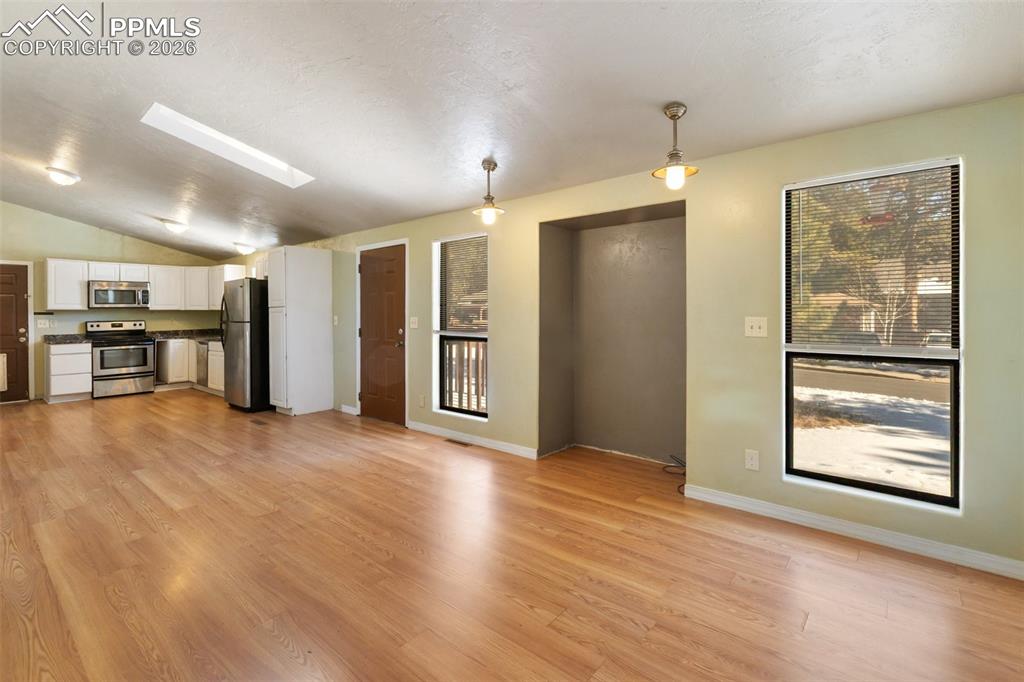 Image 2 of 36: Unfurnished living room with light wood-style floors, vaulted ceiling, and 