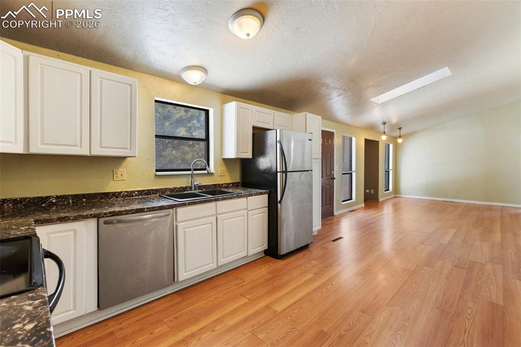 Image 31 of 36: Kitchen featuring white cabinetry, stainless steel appliances, light wood-t