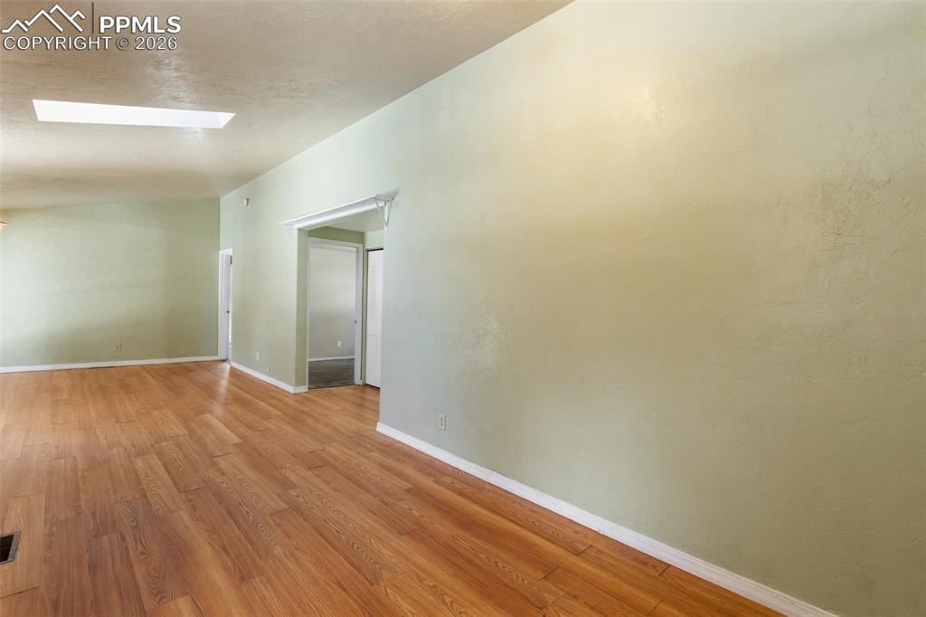 Image 32 of 36: Unfurnished room with a skylight and wood finished floors