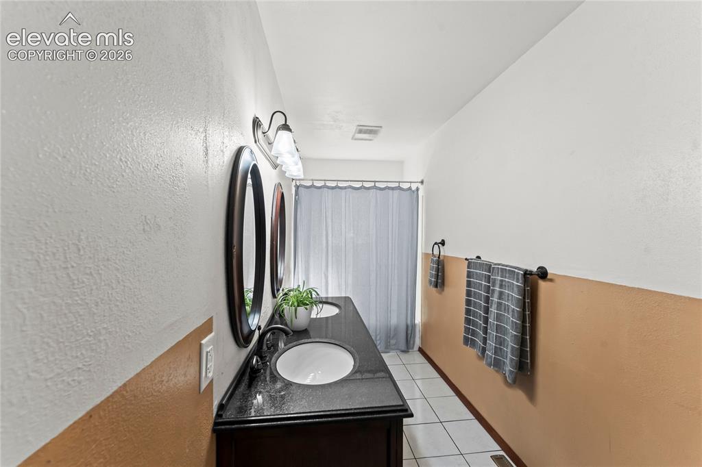 Image 18 of 45: Double vanity featuring a black countertop, dual undermount sinks, and dark