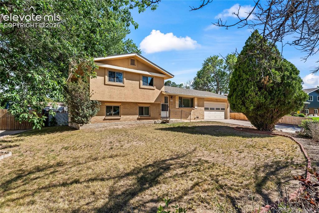 Image 38 of 45: Concrete patio area with a wooden privacy fence, mature trees, and exterior