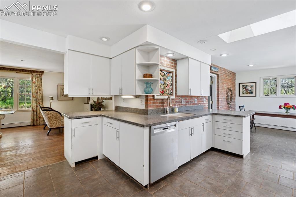 Image 10 of 33: Kitchen featuring dishwasher, a sink, a peninsula, open shelves, and plenty