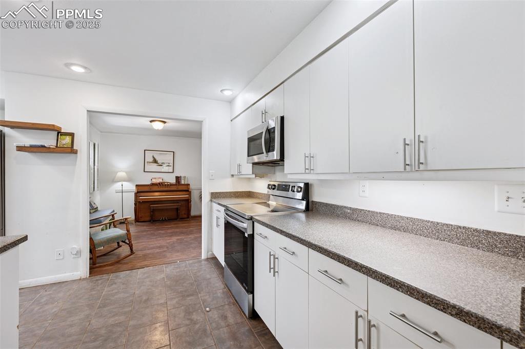 Image 11 of 33: Kitchen featuring appliances with stainless steel finishes, dark countertop