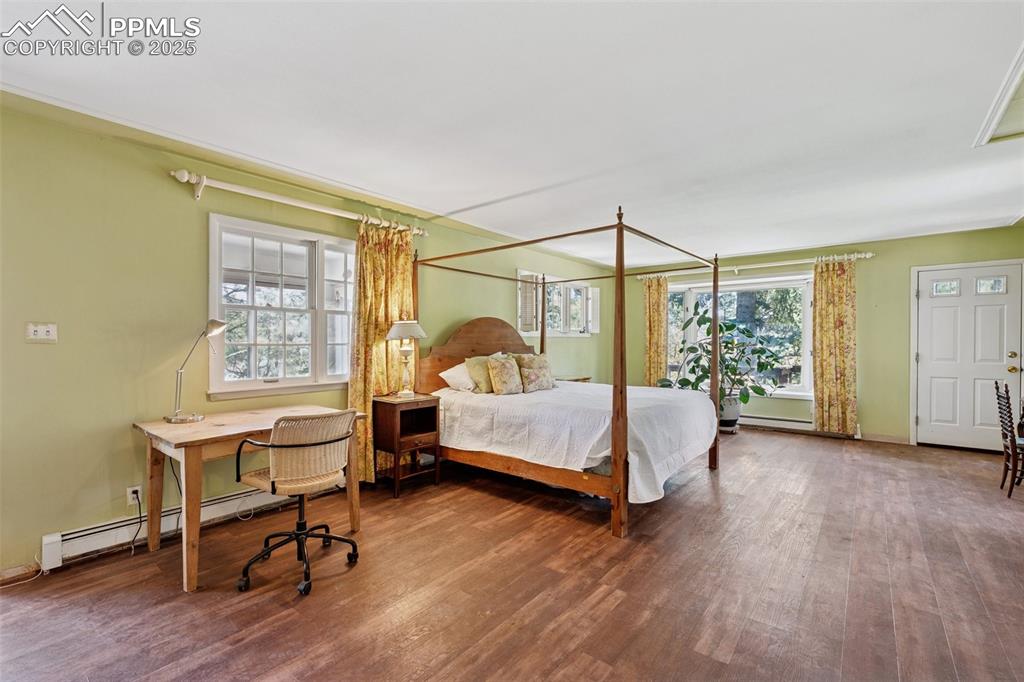 Image 18 of 33: Bedroom with wood finished floors and a baseboard radiator