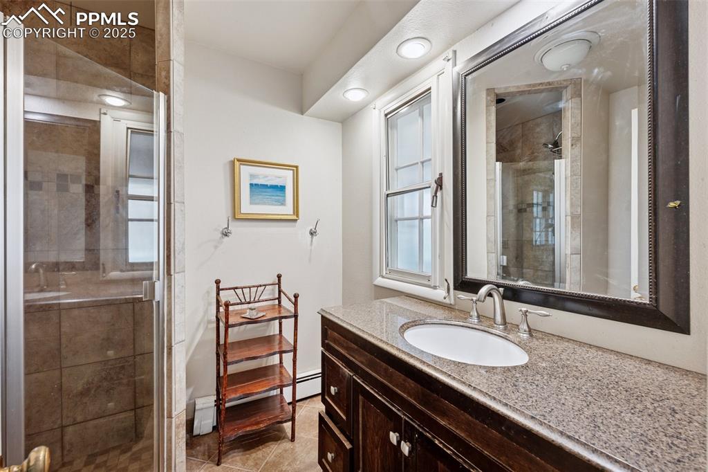 Image 19 of 33: Bathroom with a stall shower, vanity, and tile patterned flooring
