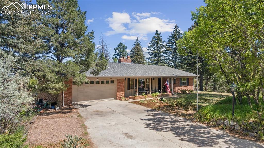 Image 2 of 33: Ranch-style house featuring brick siding, an attached garage, covered porch