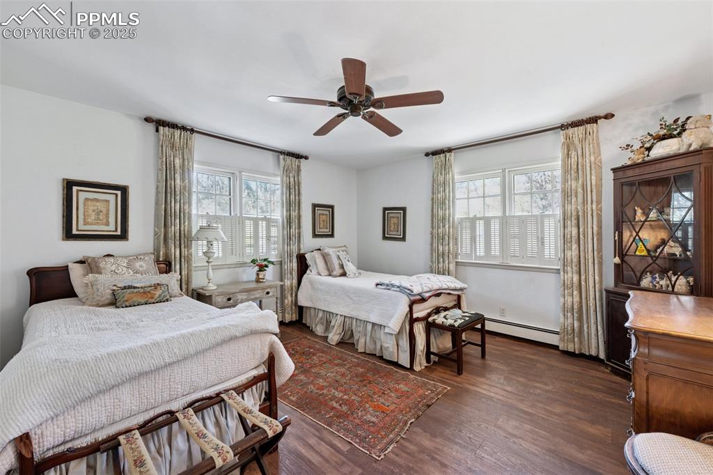 Image 20 of 33: Bedroom with baseboard heating, multiple windows, dark wood-type flooring, 