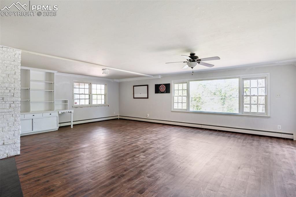 Image 23 of 33: Unfurnished living room featuring a ceiling fan, dark wood-type flooring, a
