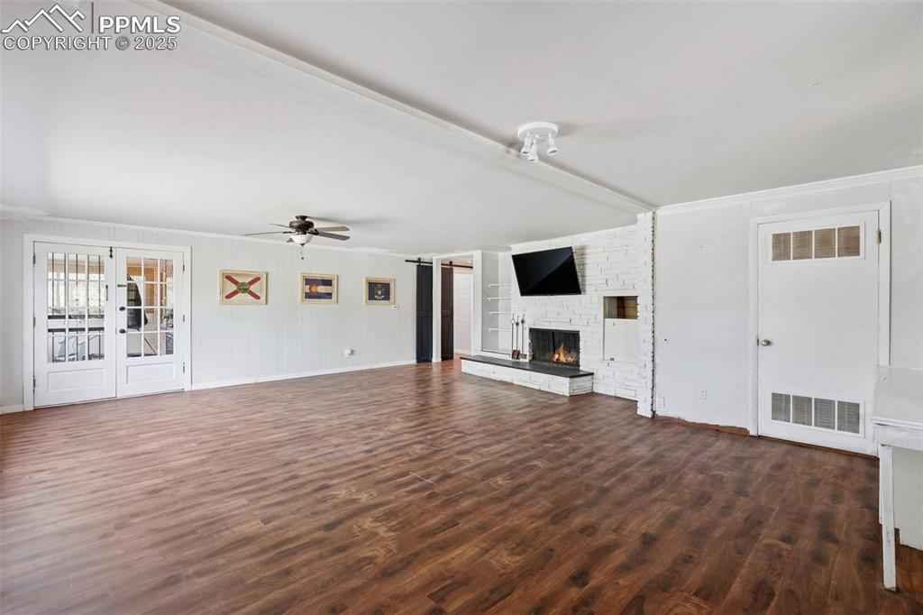 Image 25 of 33: Unfurnished living room with ceiling fan, a fireplace, dark wood finished f