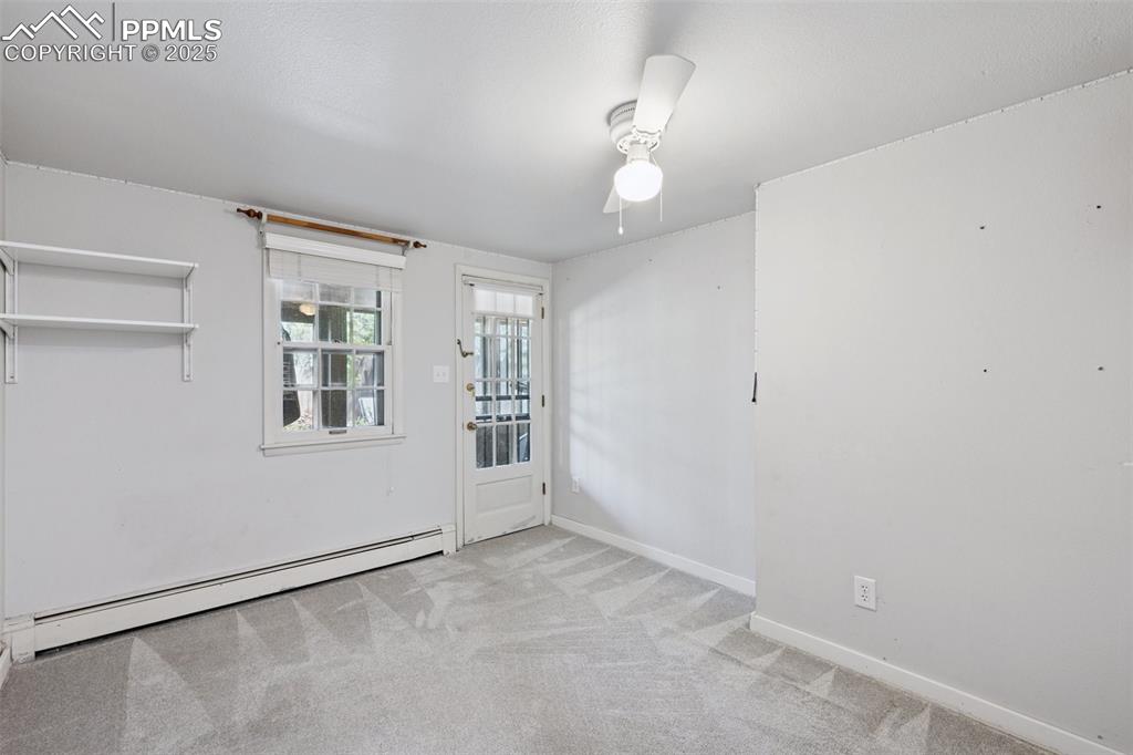Image 27 of 33: Carpeted spare room featuring baseboard heating, a ceiling fan, and baseboa