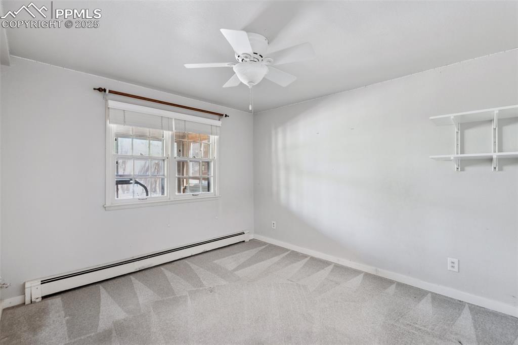 Image 29 of 33: Carpeted empty room with baseboard heating, a ceiling fan, and baseboards