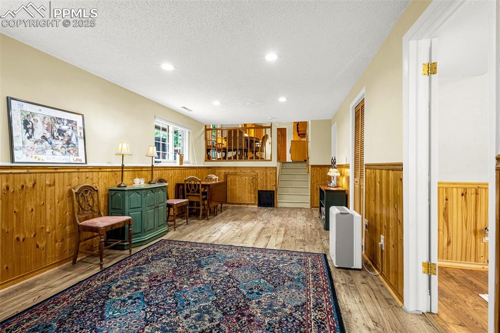 Image 10 of 33: Sitting room featuring wainscoting, wooden walls, a textured ceiling, and w