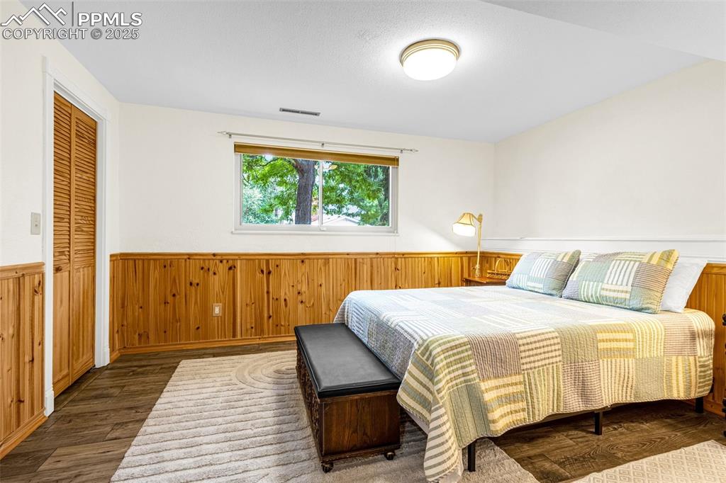 Image 12 of 33: Bedroom with wainscoting, wood finished floors, and wooden walls