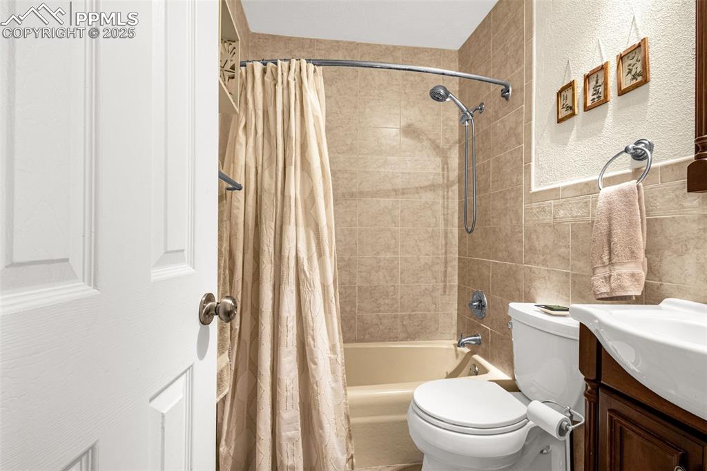 Image 13 of 33: Full bathroom with shower / bathtub combination with curtain, tile walls, a